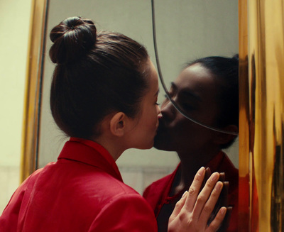 two women kissing each other in front of a mirror