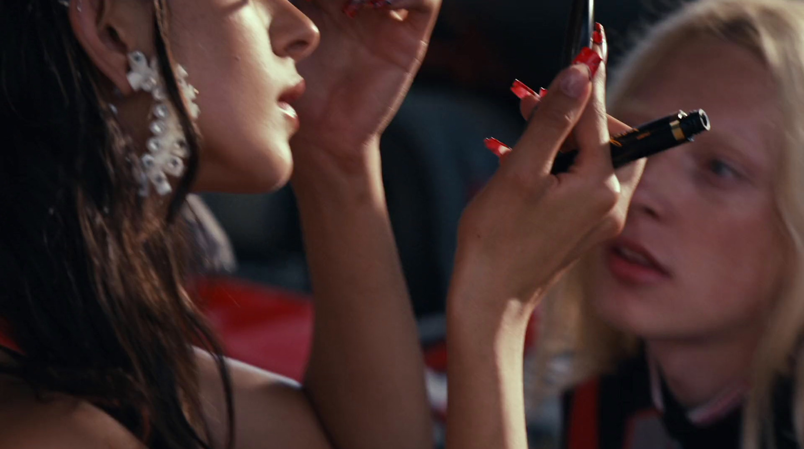 a woman is putting lipstick on another woman's face