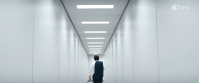 a man in a suit walking down a long hallway