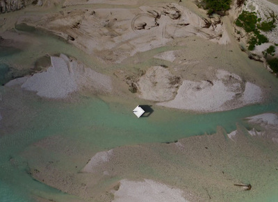 an aerial view of a house in the middle of a river