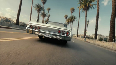 a silver car driving down a street next to palm trees