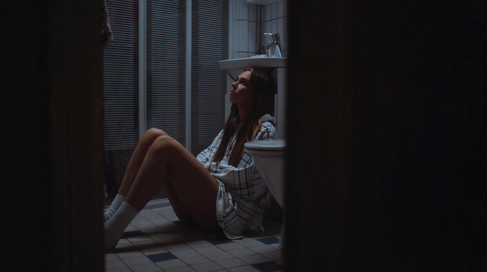 a woman sitting on the floor in a bathroom