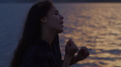 a woman smoking a cigarette near a body of water