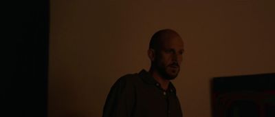 a man standing in a dark room in front of a painting