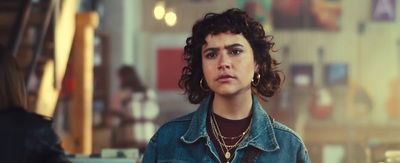 a woman with curly hair wearing a denim jacket