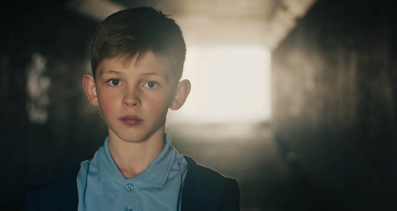 a young boy standing in a dark hallway