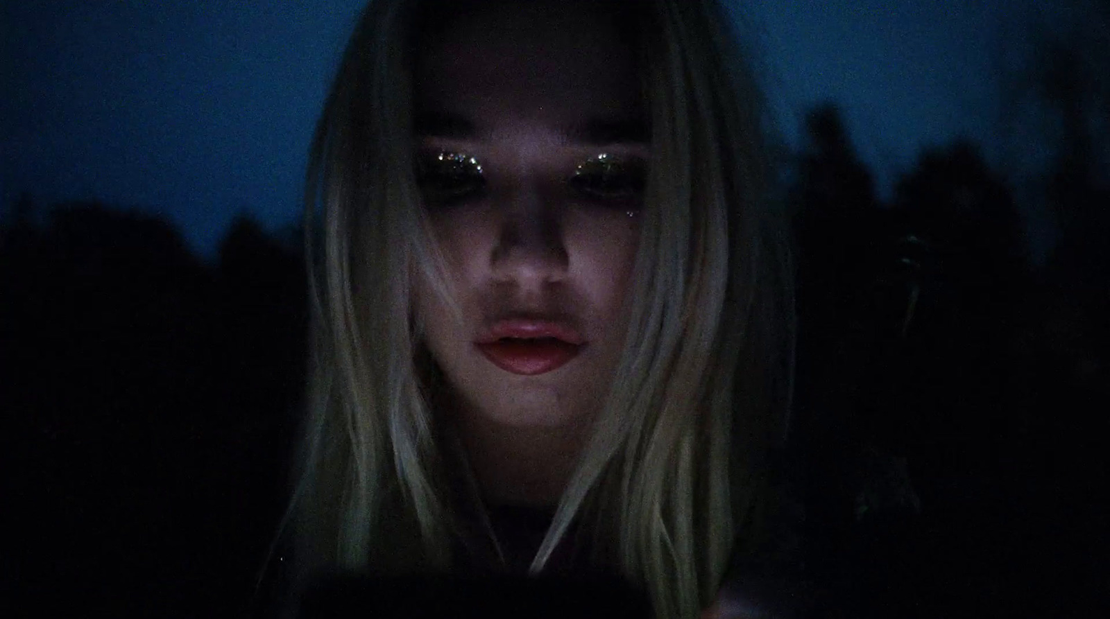 a woman looking at her cell phone in the dark