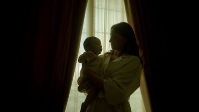 a woman holding a baby in front of a window