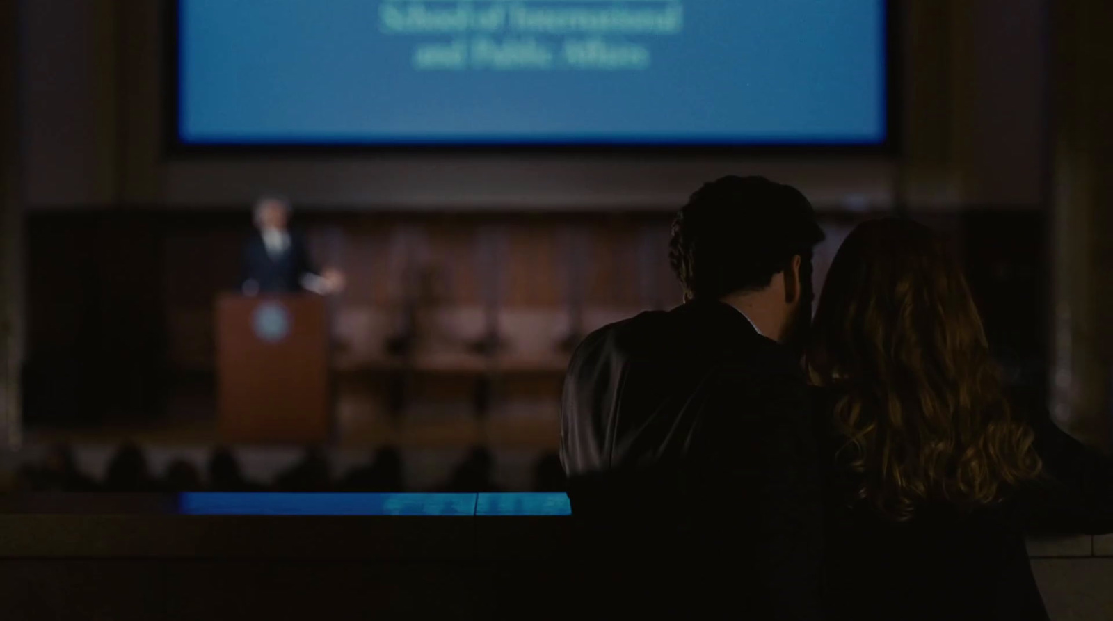 a man and a woman standing in front of a projection screen