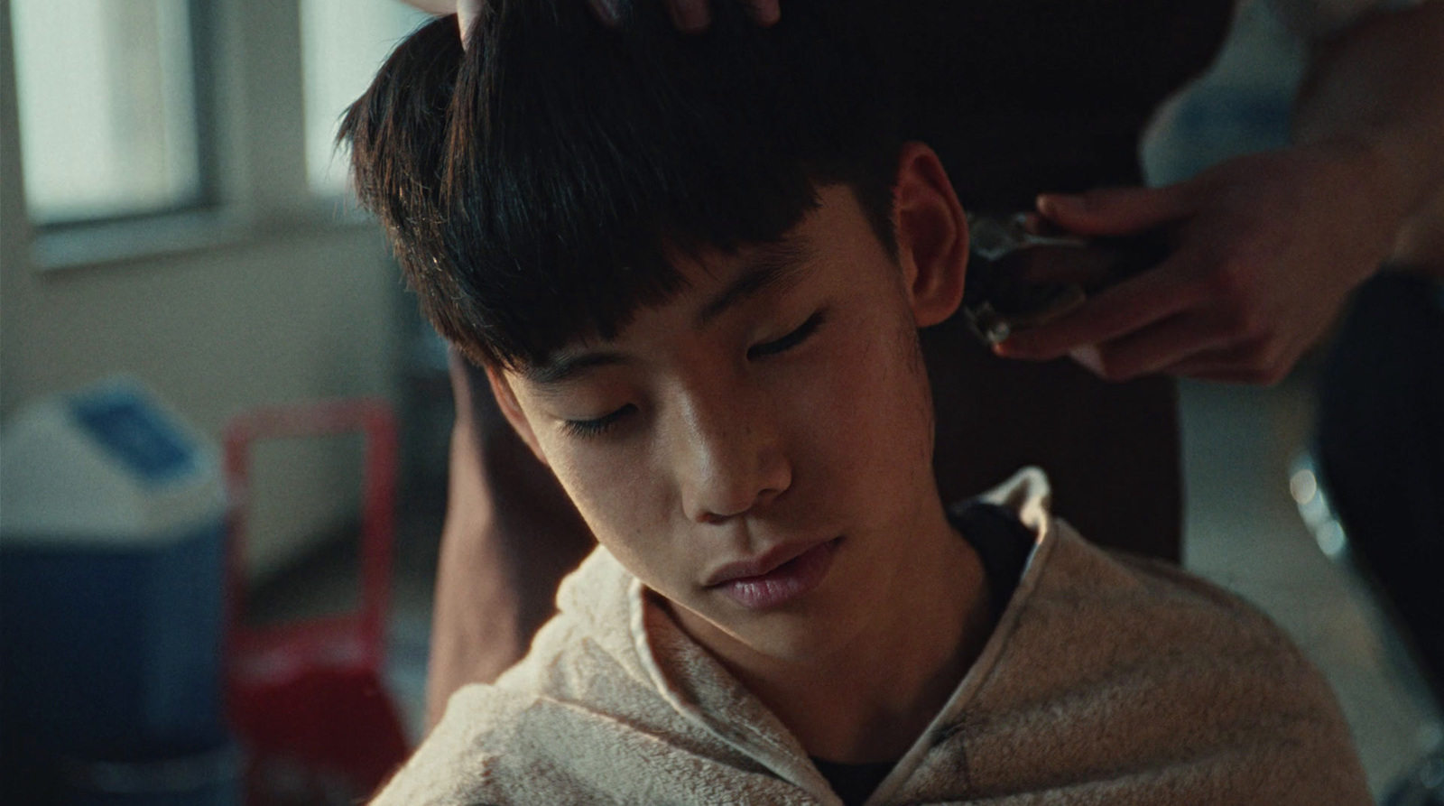 a young boy getting his hair cut by a woman