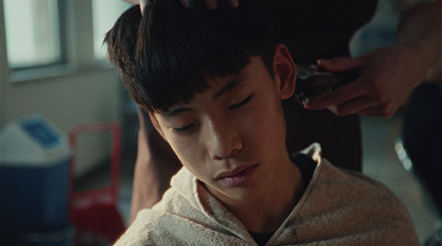 a young boy getting his hair cut by a woman