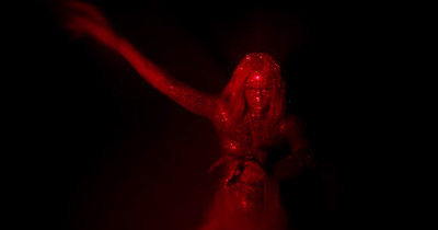 a woman in a red dress is dancing in the dark