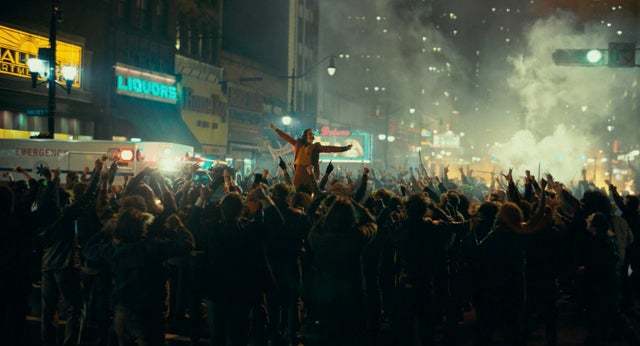 a crowd of people standing on a street at night