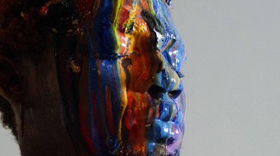 a man's face is covered in multicolored paint