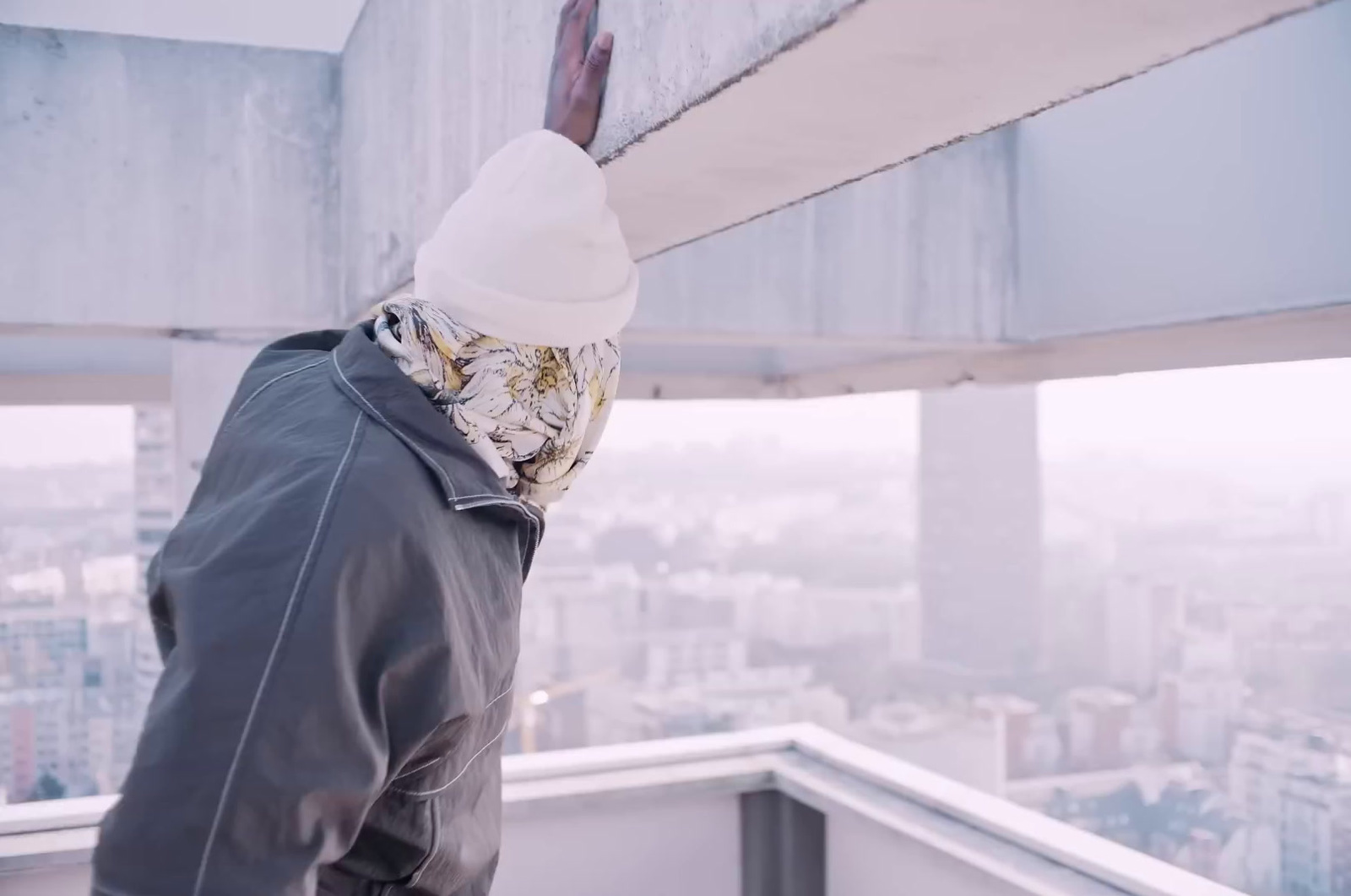 a man wearing a bandana standing on top of a building