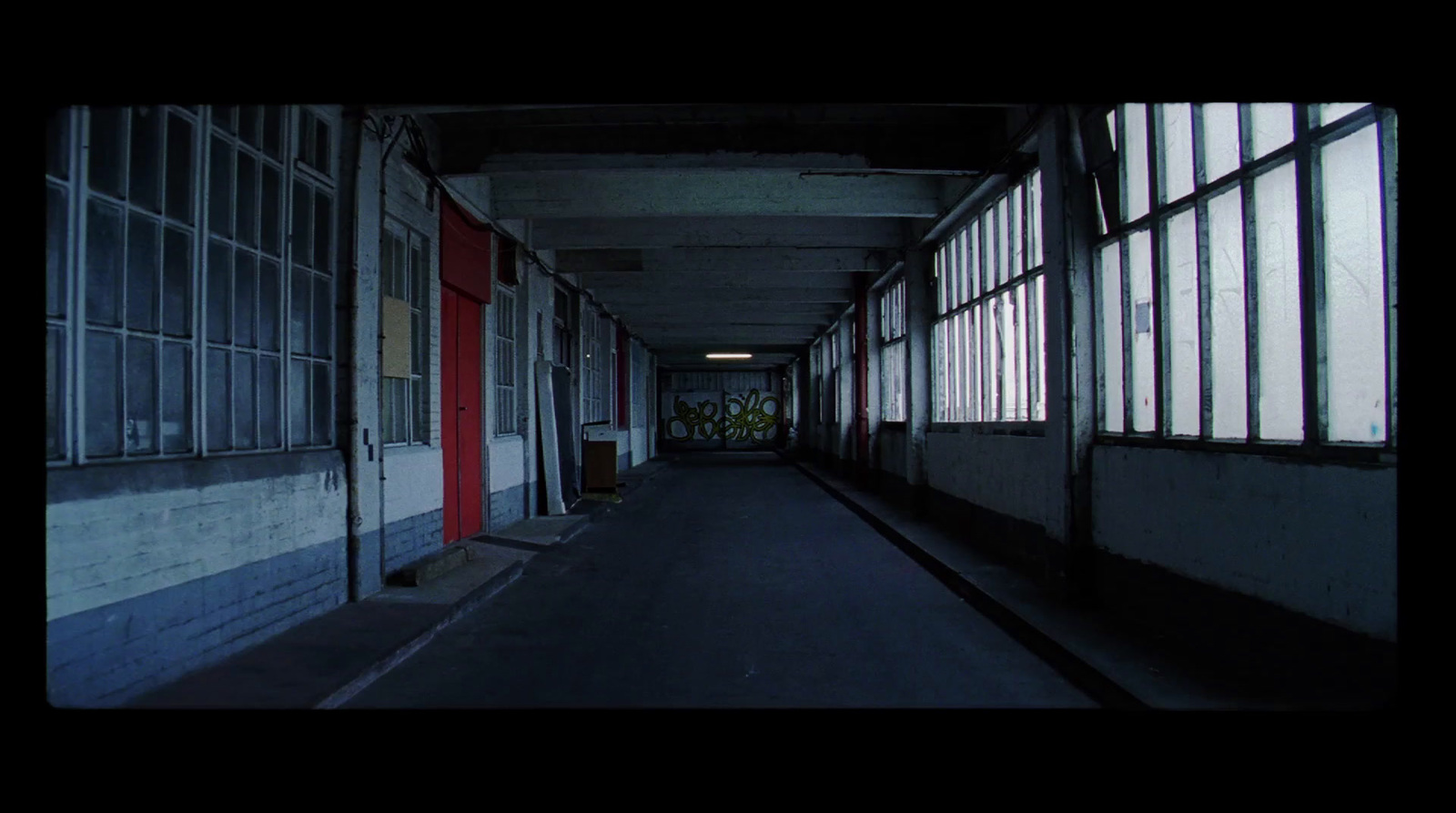 a dark hallway with windows and a red door