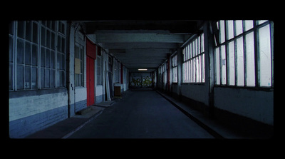 a dark hallway with windows and a red door