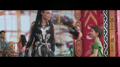 a woman standing next to a boy in front of a carnival ride