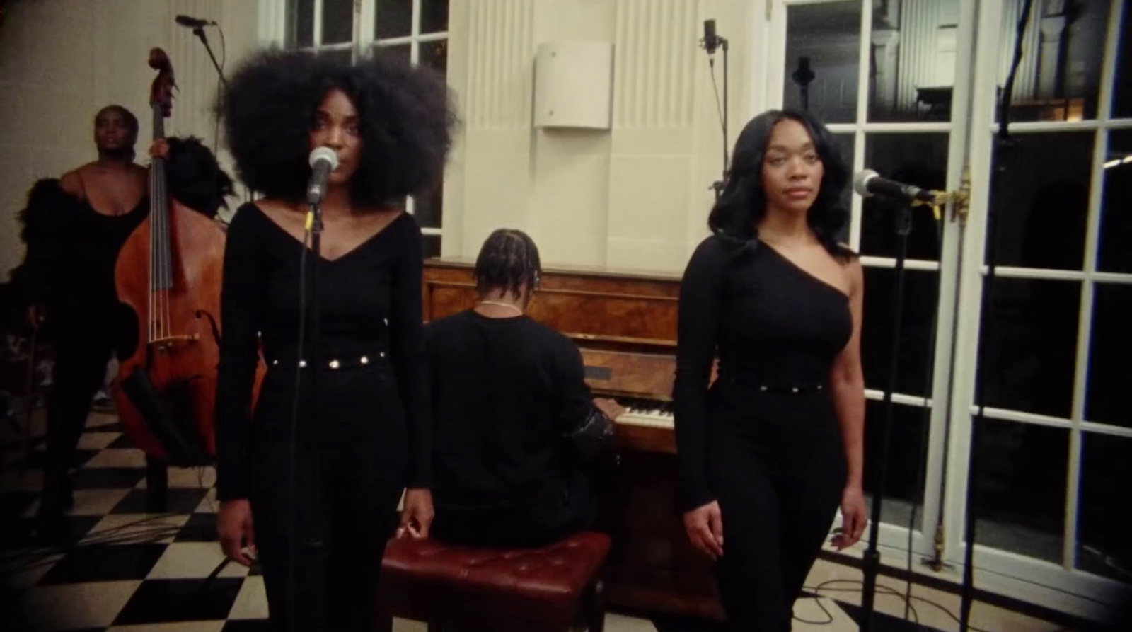 a group of women standing next to each other in front of a piano