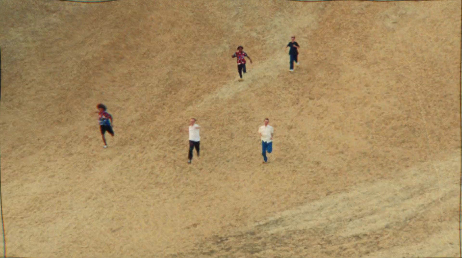 a group of people standing on top of a sandy hill