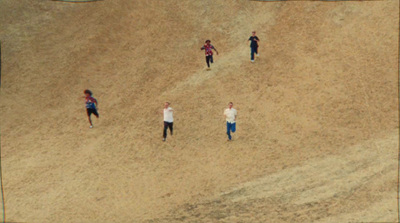 a group of people standing on top of a sandy hill