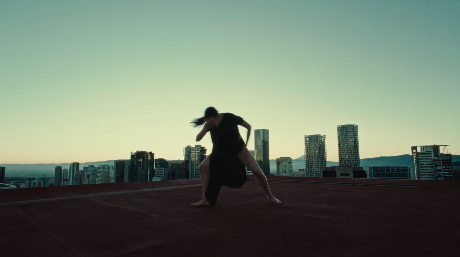 a woman in a black dress is dancing on a roof