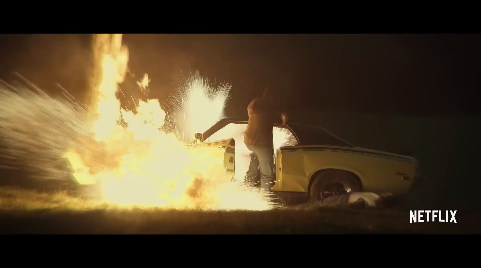 a woman standing in front of a car on fire