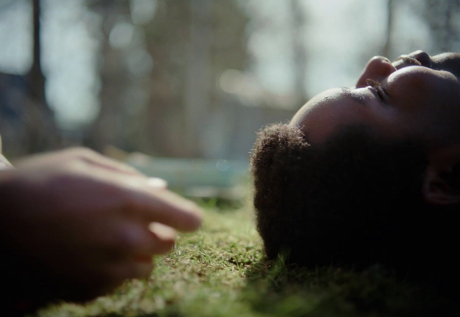 a person laying in the grass with their eyes closed