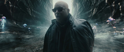 a man in a black jacket and sunglasses standing in a cave