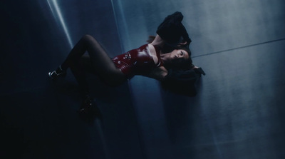 a woman in a red latex outfit leaning against a wall