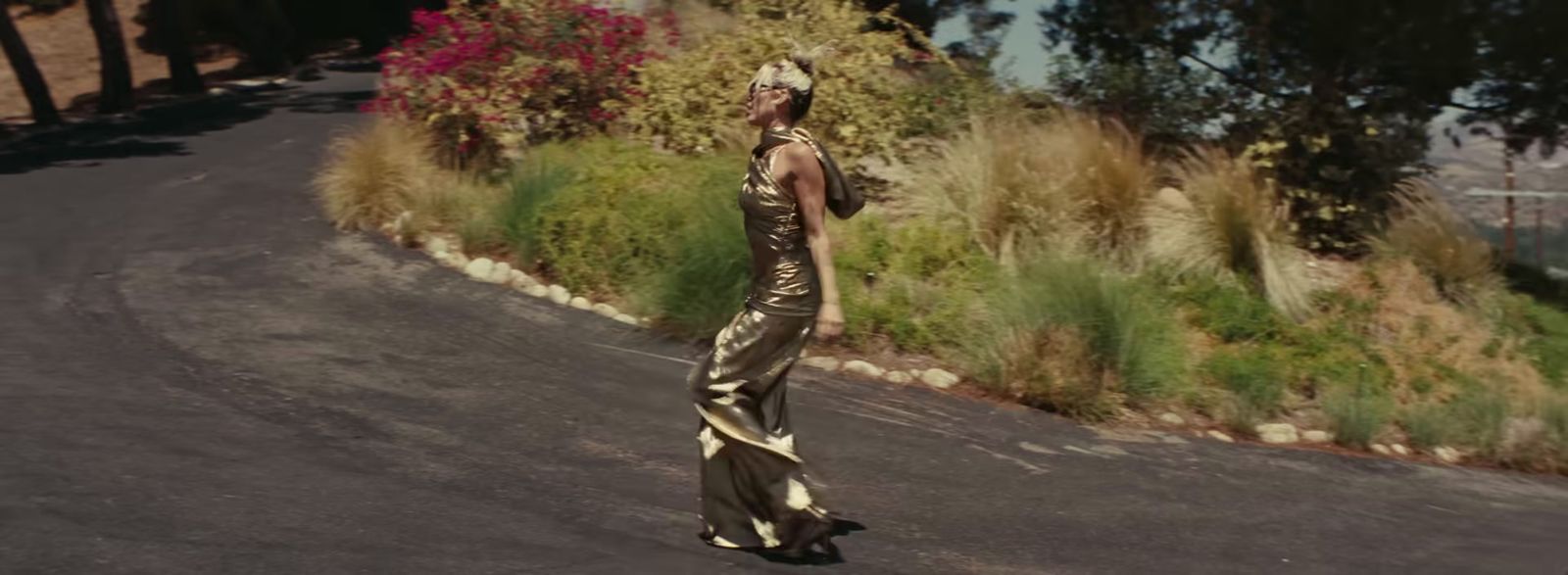 a woman in a gold dress walking down a street