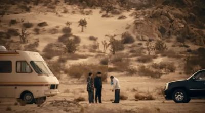 a group of people standing next to an rv in the desert