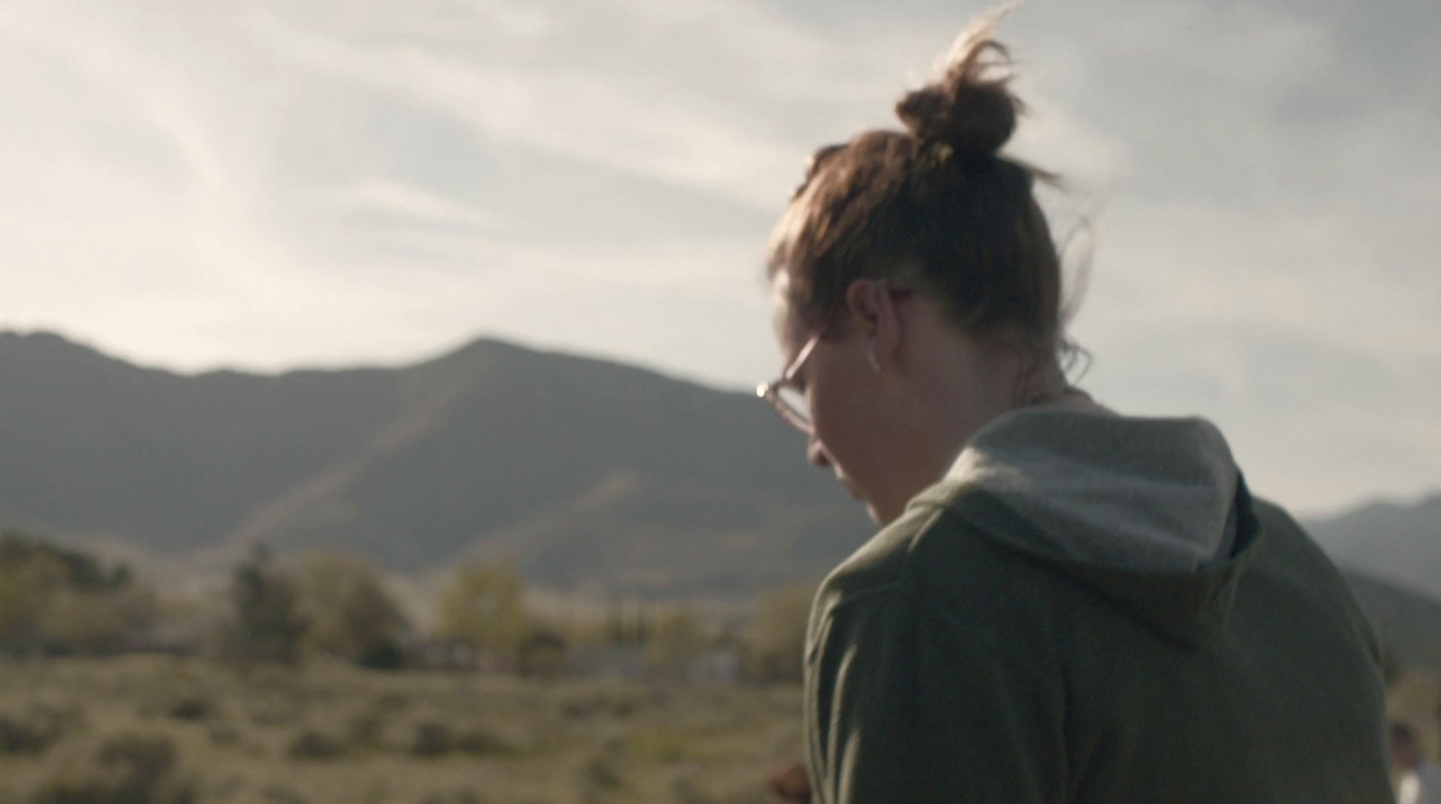 a woman standing in a field with mountains in the background