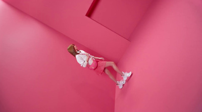 a woman in a pink room climbing up a pink wall