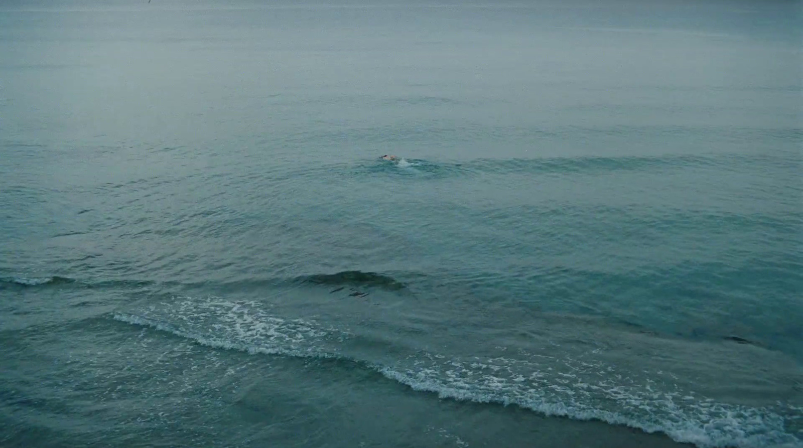 a person swimming in the ocean on a cloudy day