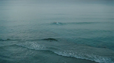 a person swimming in the ocean on a cloudy day