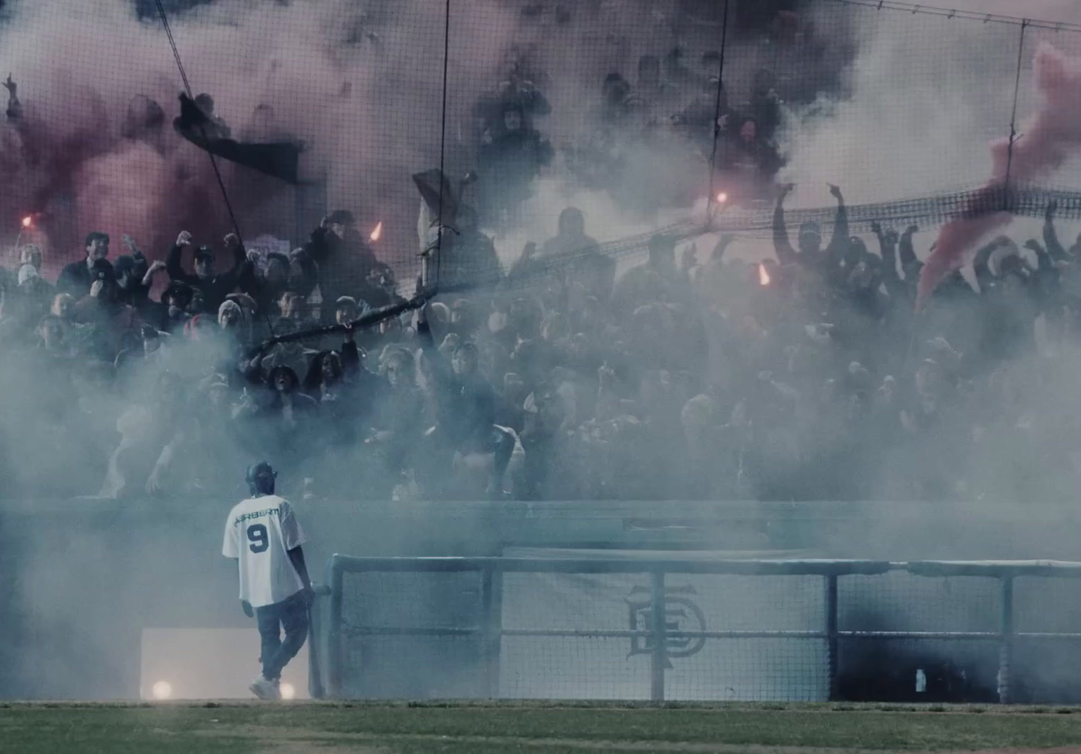 a crowd of people standing around a soccer field