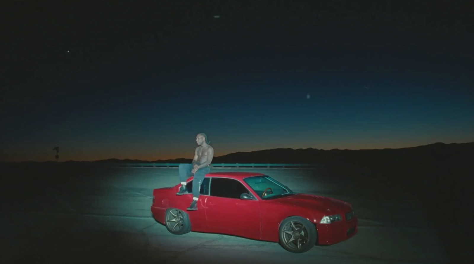 a man standing on the hood of a red car