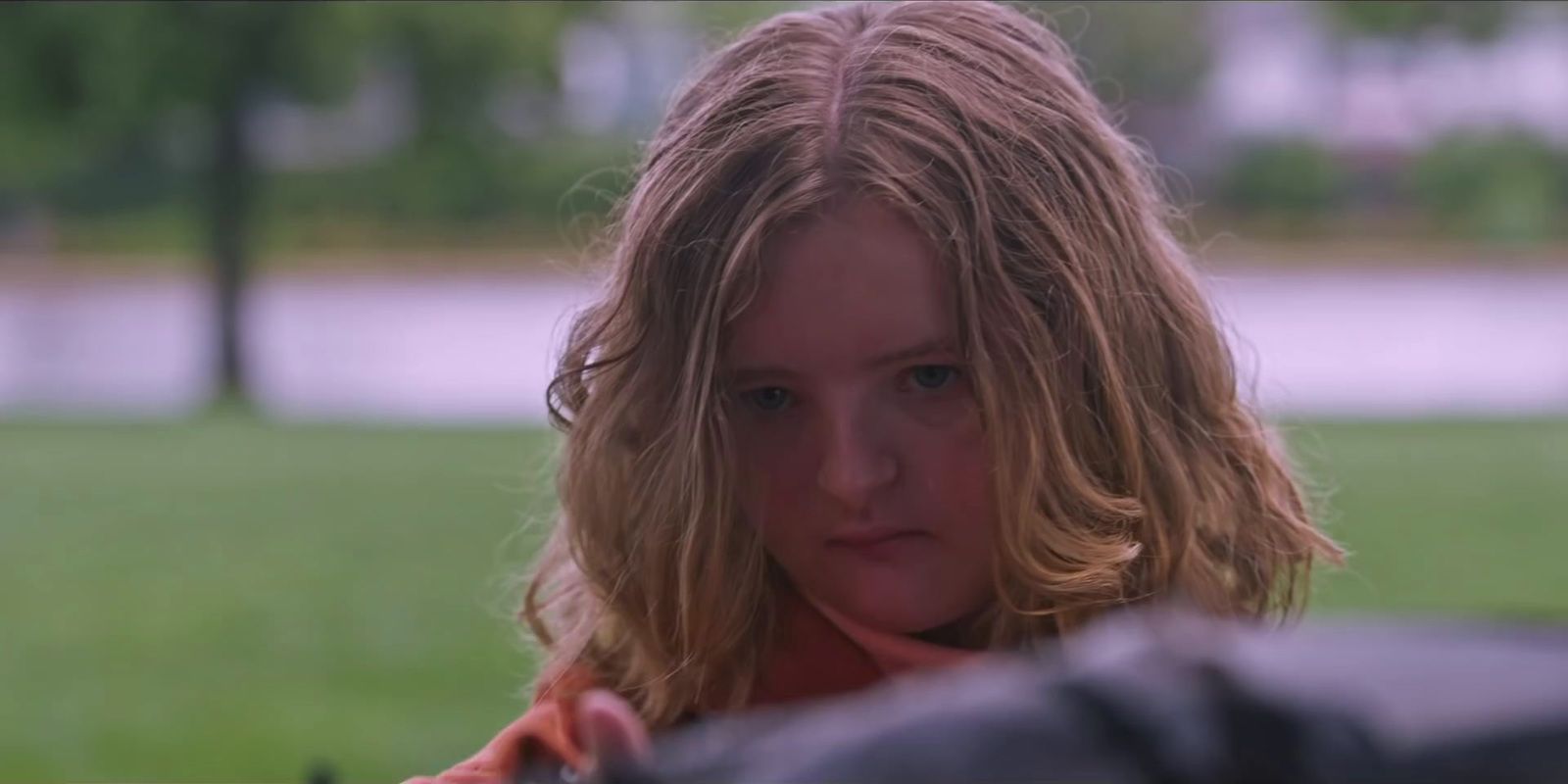 a young girl sitting on a bench in a park