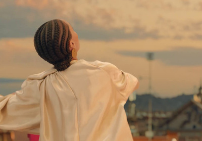 a woman with braids standing on top of a roof