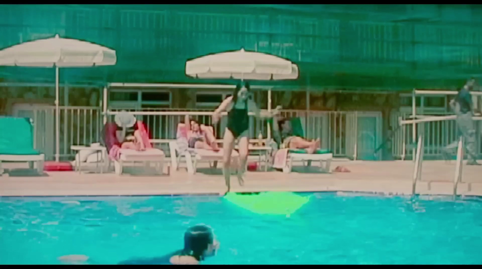 a man jumping into a swimming pool while people watch