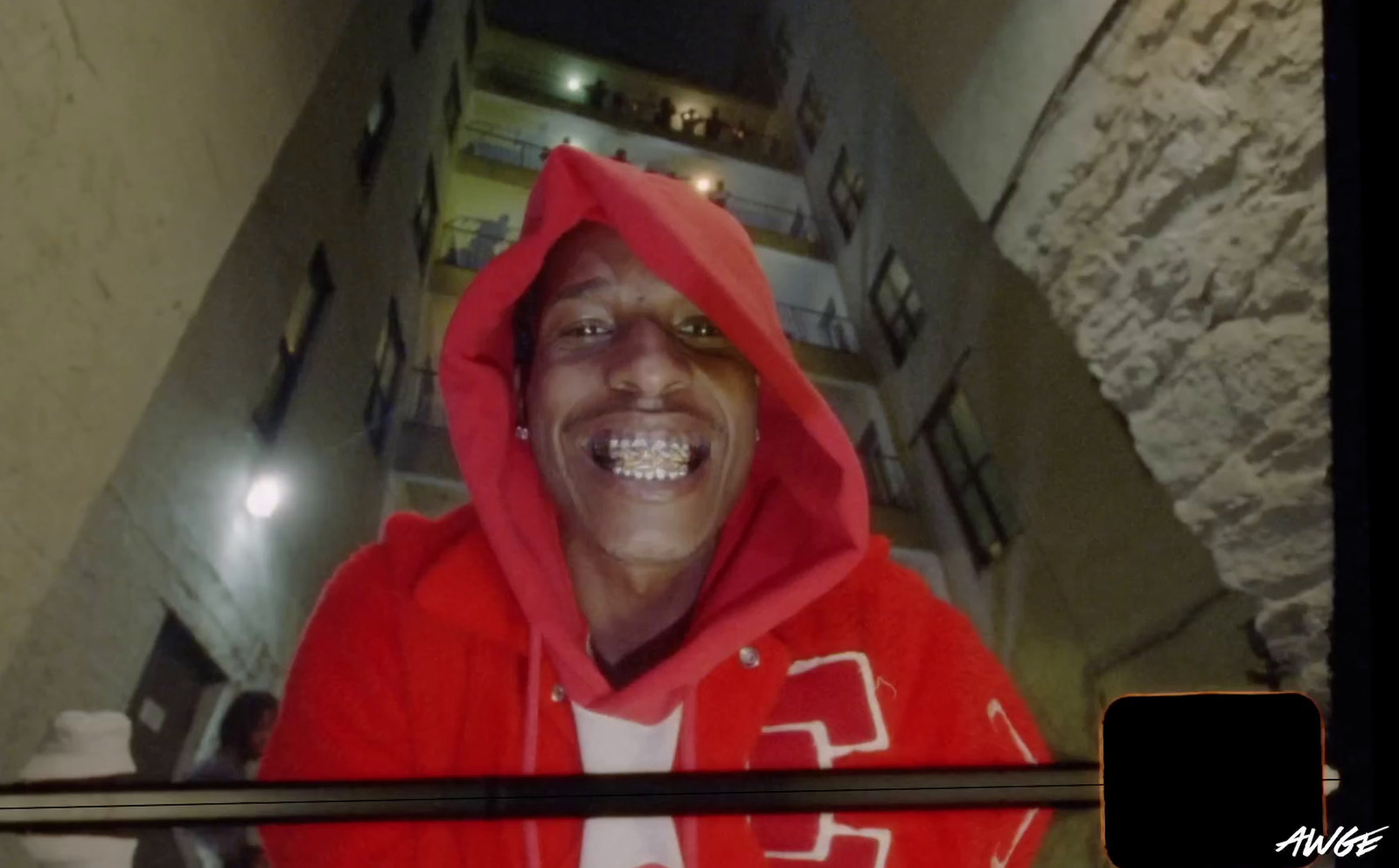 a man in a red hoodie smiles at the camera