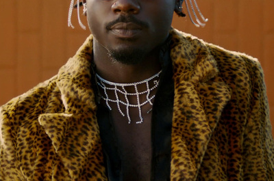 a man in a leopard print jacket with a chain around his neck