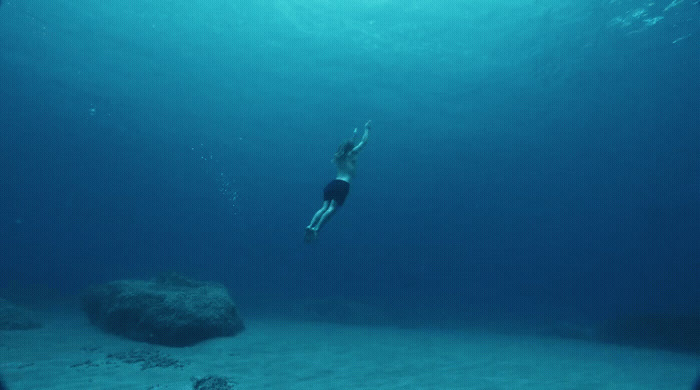 a person swimming in the water near a rock