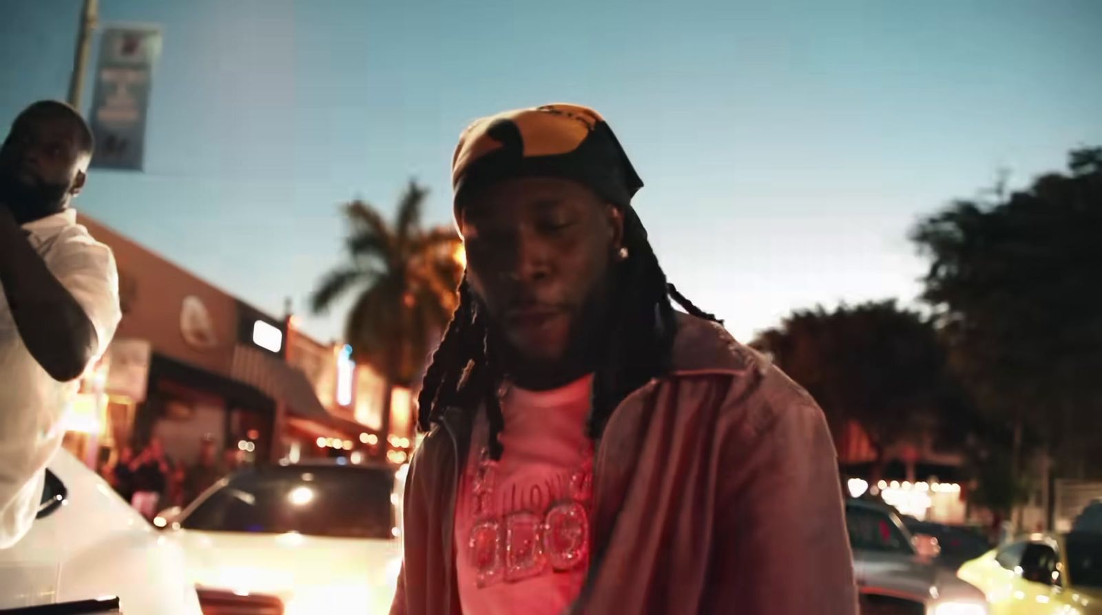 a man with dreadlocks standing in front of a car