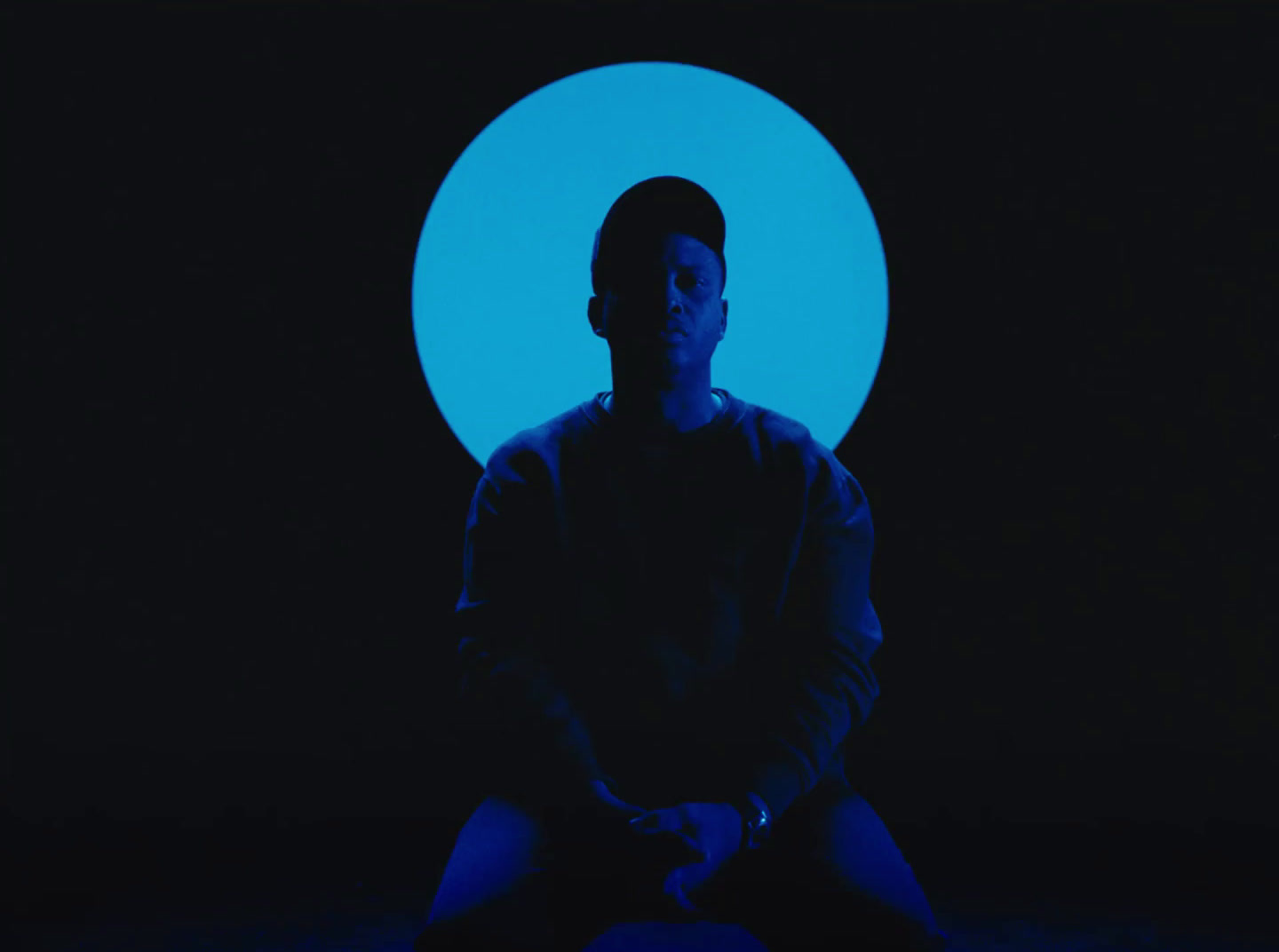 a man sitting in front of a blue circle