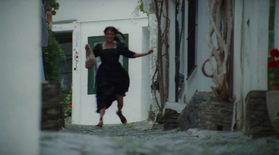 a woman in a black dress walking down a street