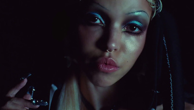 a woman with blue makeup holding a cigarette