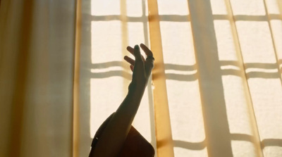 a woman standing in front of a window with her hand up