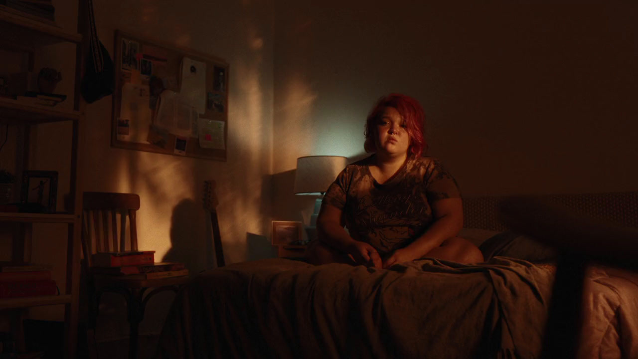 a woman sitting on a bed in a dimly lit room